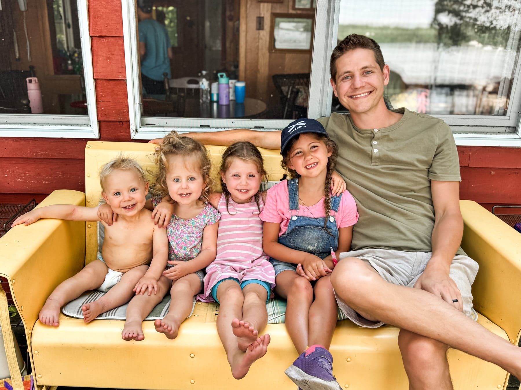A father sitting outside with four young children