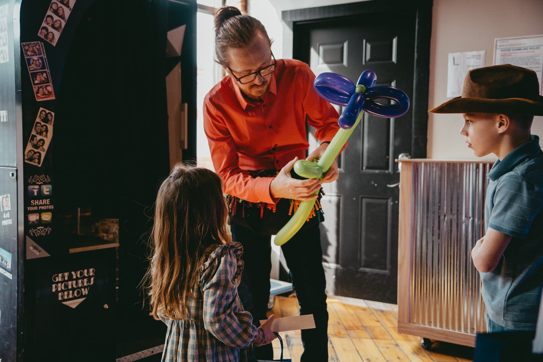 A father making a balloon flower while children watch