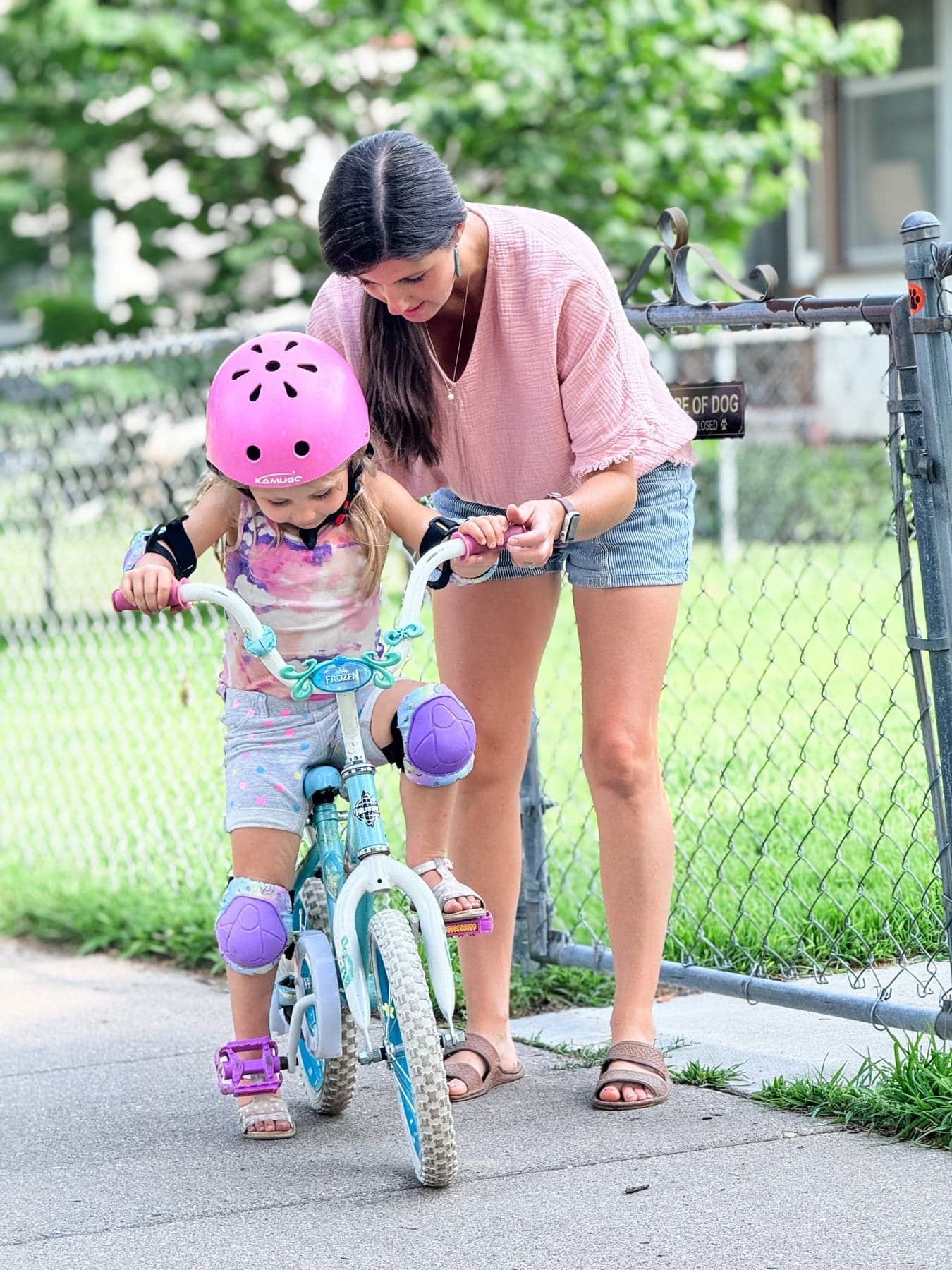 A mother helping her young child learn to ride a bicycle